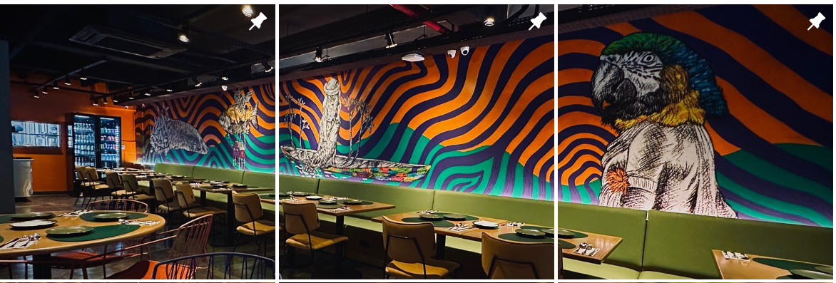 Salão de restaurante com um painel colorido com referências à Amazônia